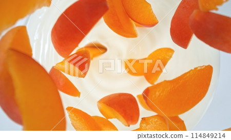 Fresh apricots pieces falling into cream, top down view 114849214