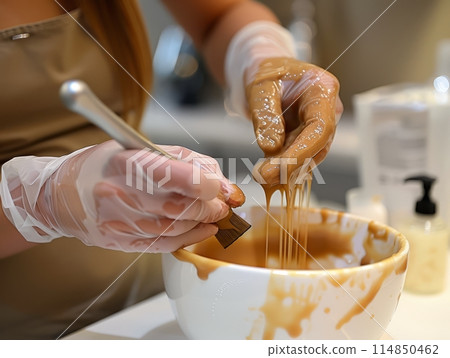 Close-up hands of cosmetologist in gloves applying paste for sugaring depilation on female leg , hair removal beauty procedure. Close-up hands of cosmetologist in gloves applying paste for sugaring depilation on female leg , hair removal beauty procedure. 114850462