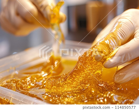 Close-up hands of cosmetologist in gloves applying paste for sugaring depilation on female leg , hair removal beauty procedure. Close-up hands of cosmetologist in gloves applying paste for sugaring depilation on female leg , hair removal beauty procedure. 114850577