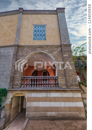 Serene view of a rustic style building featuring an arched wooden balcony, and detailed window grills 114850939