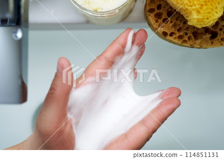 Foam cleanser in female hands over the sink. 114851131