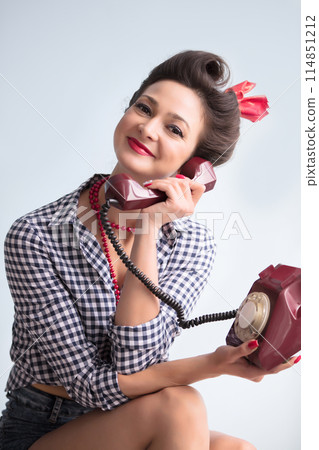 Woman in the style of the fifties. Beautiful retro girl with an old telephone. Woman in the style of the fifties. Beautiful retro girl with an old telephone. 114851212