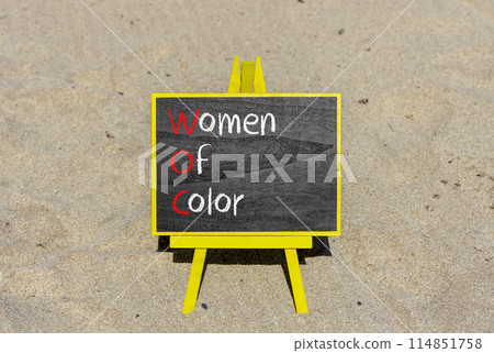 WOC women of color symbol. Concept words WOC women of color on beautiful yellow blackboard. Beautiful sand background. Business WOC women of color social issues concept. Copy space. 114851758
