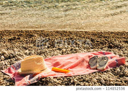 Sun hat and flip flops on stone beach 114852536