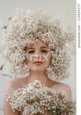 Portrait of sensual blond woman with flowers. Beautiful girl with flowers in her hair. Summer Beauty. Art in a contemporary style. A gypsophila wreath on a white background. Perfume, cosmetics concept Portrait of sensual blond woman with flowers. Beautiful girl with flowers in her hair. Summer Beauty. Art in a contemporary style. A gypsophila wreath on a white background. Perfume, cosmetics concept 114854157