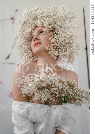 Portrait of sensual blond woman with flowers. Beautiful girl with flowers in her hair. Summer Beauty. Art in a contemporary style. A gypsophila wreath on a white background. Perfume, cosmetics concept Portrait of sensual blond woman with flowers. Beautiful girl with flowers in her hair. Summer Beauty. Art in a contemporary style. A gypsophila wreath on a white background. Perfume, cosmetics concept 114854158