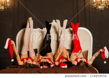 Four pretty women with curly hair and red Christmas lingerie. New year background. Four pretty women with curly hair and red Christmas lingerie. New year background. 114854438