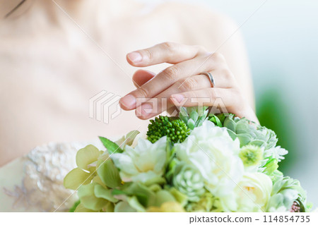 Bride putting on wedding ring and engagement ring 114854735