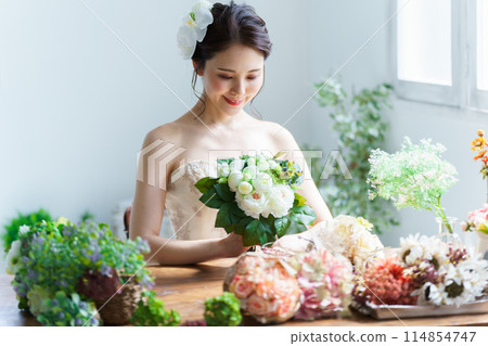 一個穿著婚紗的女人被花束包圍 一個穿著婚紗的女人被花束包圍 114854747