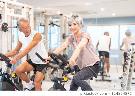 Senior couple doing aerobic exercise at the gym Senior couple doing aerobic exercise at the gym 114854875