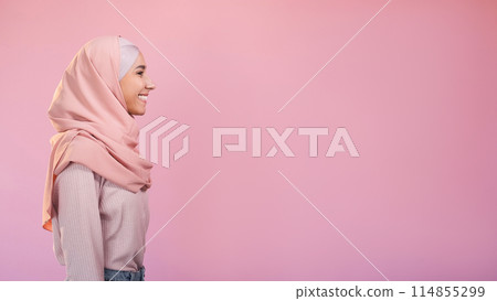 Muslim beauty. Friendly expression. Optimistic attitude. Profile of cheerful woman in hijab isolated on pastel pink empty space background. 114855299