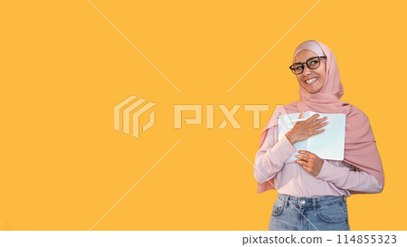 Writer inspiration. Smart people. Intelligent enthusiastic smiling woman in hijab glasses with pen journal book for notes isolated on yellow empty space background. Writer inspiration. Smart people. Intelligent enthusiastic smiling woman in hijab glasses with pen journal book for notes isolated on yellow empty space background. 114855323