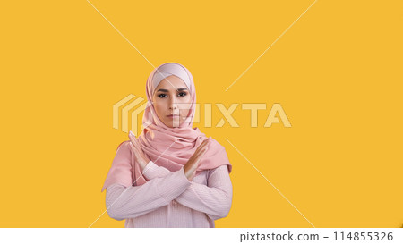 No gesture. Stop rejection. Refusing reaction. Concerned woman in hijab showing refusal crossed hands isolated on orange empty space background. 114855326
