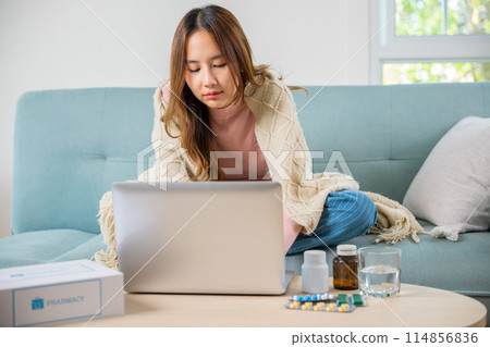 Business female sick she taking pills for flu while work with laptop keyboard, Asian sick woman covered blanket suffering from covid-19 virus but still working at home with laptop computer Business female sick she taking pills for flu while work with laptop keyboard, Asian sick woman covered blanket suffering from covid-19 virus but still working at home with laptop computer 114856836