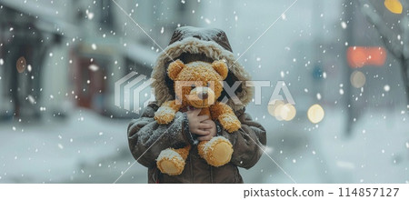 lonely homeless child with a toy bear in his hands on a city street, winter snowy day 114857127