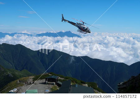 A helicopter transporting luggage to a mountain hut 114857172