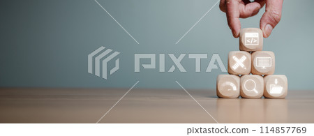 Web design and development concept, Hand holding wooden block on desk with web coding, design, coding, testing, web analytics and content management icon on virtual screen. 114857769