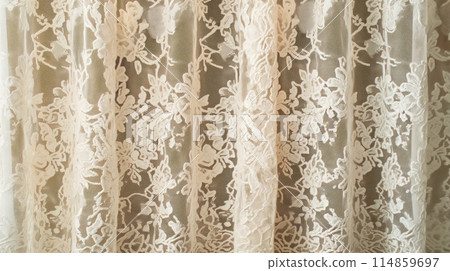 Delicate beige lace curtain displaying intricate floral embroidery, perfect for adding a touch of elegance to any room. Delicate beige lace curtain displaying intricate floral embroidery, perfect for adding a touch of elegance to any room. 114859697
