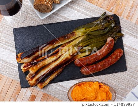 Grilled sausage and delicious calsot served on plate with sauce, traditional dish of Catalonia Grilled sausage and delicious calsot served on plate with sauce, traditional dish of Catalonia 114859957