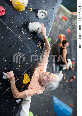 elderly active female pensioner reached top of bouldering wall elderly active female pensioner reached top of bouldering wall 114860010