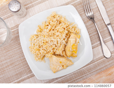 Tender meat of baked chicken breast is garnished with boiled basmati rice. 114860057