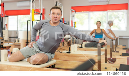 Adult man doing stretching on pilates machine 114860438
