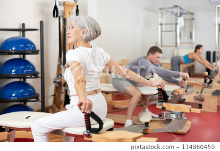 Senior woman performs Pilates exercises for weight loss and toning muscles of back and shoulders Senior woman performs Pilates exercises for weight loss and toning muscles of back and shoulders 114860450