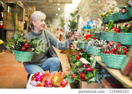 Cheerful senior woman looking for New Year decorations in store 114860583
