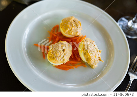 Several boiled chicken eggs with meat filling are laid out on plate. Several boiled chicken eggs with meat filling are laid out on plate. 114860678
