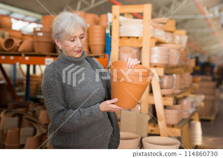 Senior woman looking for pots for growing plants in greenhouse 114860730