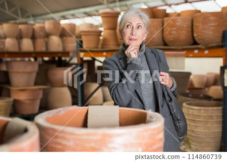 Senior woman looking for pots for growing plants in greenhouse 114860739