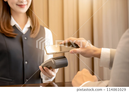 A woman making a contactless payment using her smartphone 114861029