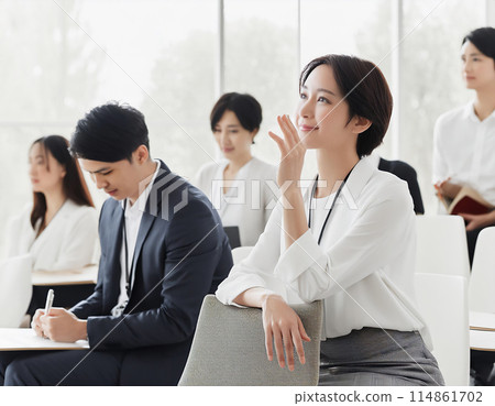 A woman attending a seminar and asking a question A woman attending a seminar and asking a question 114861702
