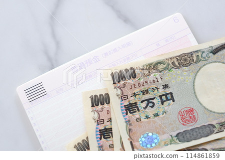 An open bank passbook and a 10,000 yen note on a table 114861859