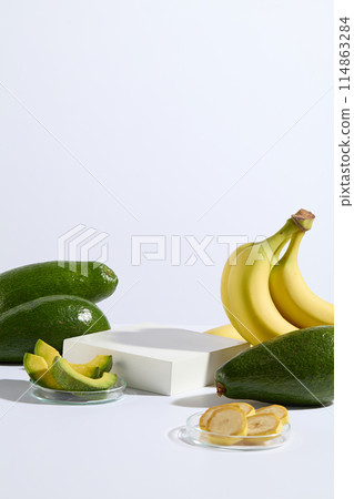 Creative template for advertising with an empty rectangular platform in center, fresh avocado and banana decorated around, avocado and banana cut into slices put on glass dish displayed in front Creative template for advertising with an empty rectangular platform in center, fresh avocado and banana decorated around, avocado and banana cut into slices put on glass dish displayed in front 114863284