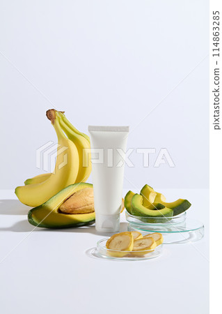 Mockup for advertising of avocado and banana concept on white background, empty label cosmetic sample tube placed in center for adding packaging of brand. Copy space for adding text 114863285