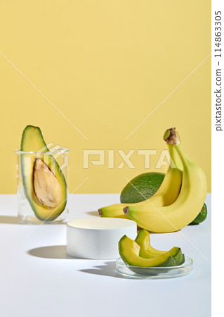 Unique design for advertise product manufactured from banana and avocado on yellow background with a blank platform displayed in the middle of white table for showing product, copy space for text 114863305