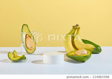 The podium in round shaped with space above for displaying product placed next to a bunch of banana, few fresh avocados, a beaker with a half avocado in and a glass dish of avocado pieces The podium in round shaped with space above for displaying product placed next to a bunch of banana, few fresh avocados, a beaker with a half avocado in and a glass dish of avocado pieces 114863306