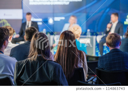 Audience listening to panel discussion at business conference 114863743