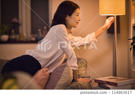 Night routine of a business woman who takes off her jacket and turns on the light at the stand. 114863817