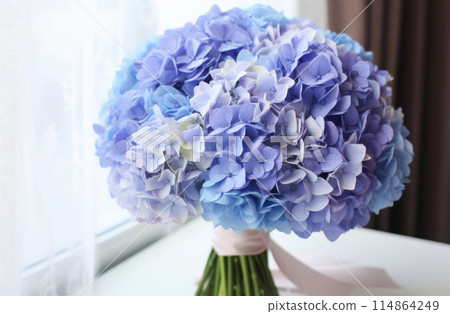 A bouquet of blue hydrangea on a table. 114864249