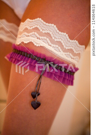 Elegant bridal garter with lace and purple ribbon, ideal for a charming wedding accessory 114864618