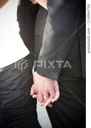 A couple holding hands at a wedding symbolizes their love, unity, and commitment towards each other A couple holding hands at a wedding symbolizes their love, unity, and commitment towards each other 114864756
