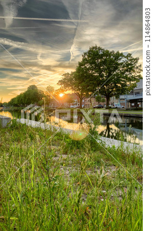 Tranquil Sunset Over Riverside Village at Days End serene and picturesque beauty of nature Tranquil Sunset Over Riverside Village at Days End serene and picturesque beauty of nature 114864803