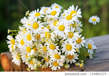 A bouquet of white daisies is arranged on a wooden table 114865173