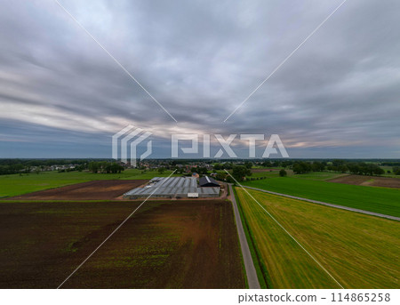 Capturing an extensive farmland on a cloudy day near rural structures with an aerial perspective 114865258