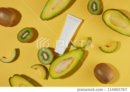 Concept of natural fruits with avocado and kiwi cut in slices displayed around a blank label cosmetic tube. Cosmetic package mock up collection for cream, foams, shampoo Concept of natural fruits with avocado and kiwi cut in slices displayed around a blank label cosmetic tube. Cosmetic package mock up collection for cream, foams, shampoo 114865767