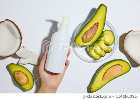 A large petri dish of avocado slices and halves arranged on white background. Female hand model holding unlabeled pump bottle for branding mockup A large petri dish of avocado slices and halves arranged on white background. Female hand model holding unlabeled pump bottle for branding mockup 114866050