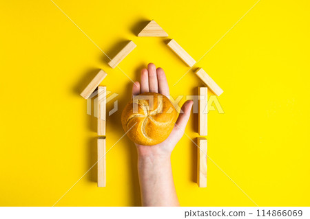 Hand holding money coins close to bread on yellow background 114866069