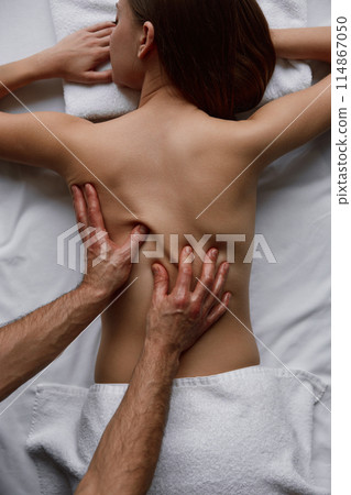 Top view of attractive woman back spine and massage therapist hands Top view of attractive woman back spine and massage therapist hands 114867050